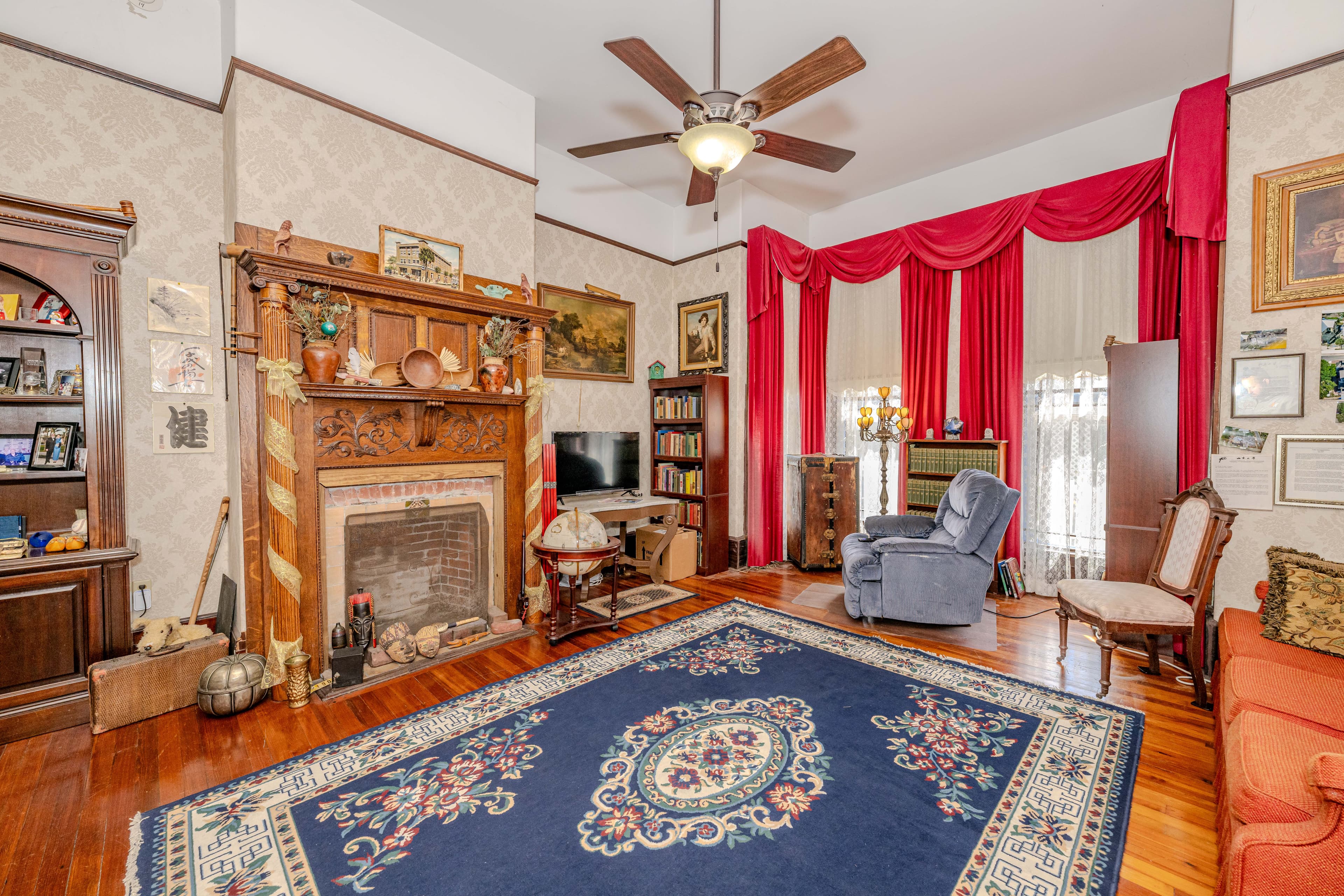 Cozy living room featuring an ornate fireplace, vintage decor, and a colorful area rug.